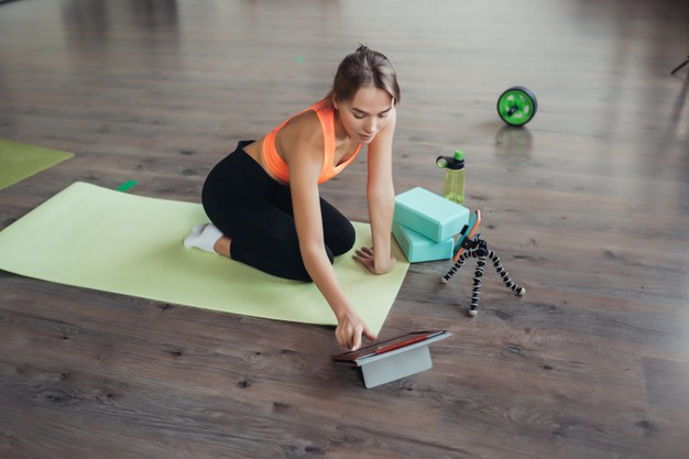 beautiful-young-woman-practicing-yoga-is-engaged-with-teacher-online-via-tablet-home-sports-concept_1153-7856