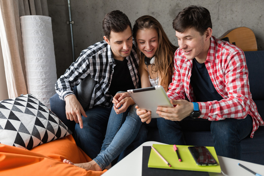 happy-young-people-using-tablet-students-learning-having-fun-friends-party-home-hipster-company-together-two-men-one-woman-smiling-positive-online-education