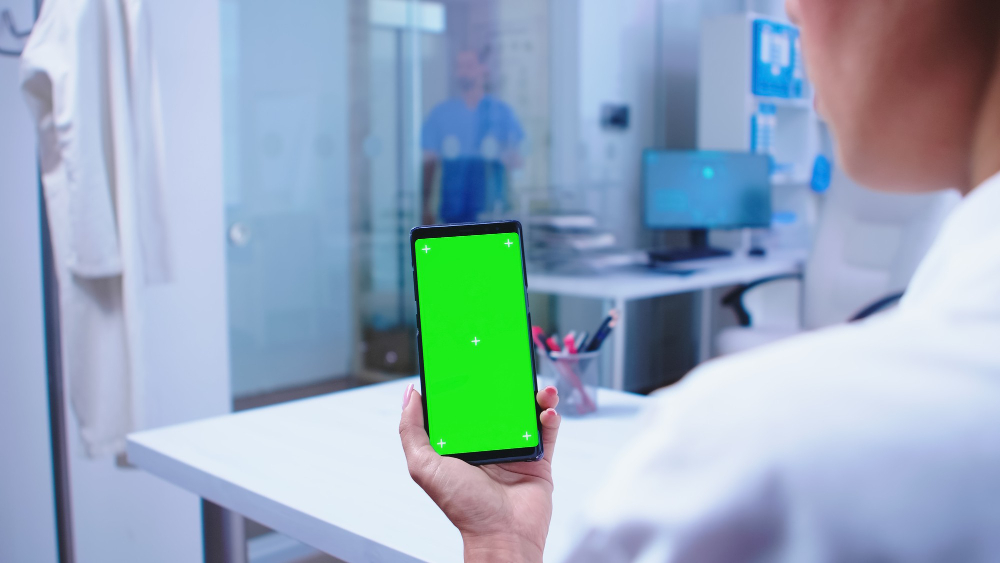 medical-physician-looking-phone-with-green-screen-hospital-cabinet-nurse-getting-out-elevator-healthcare-specialist-hospital-cabinet-using-smartphone-with-mockup