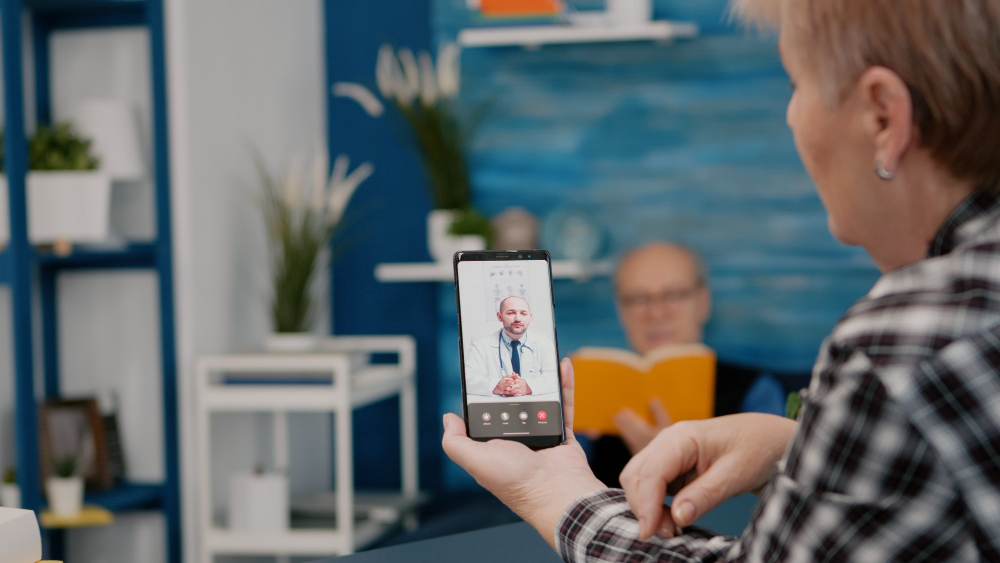 middle-aged-woman-talking-video-conference-calling-with-remote-doctor-using-smartphone