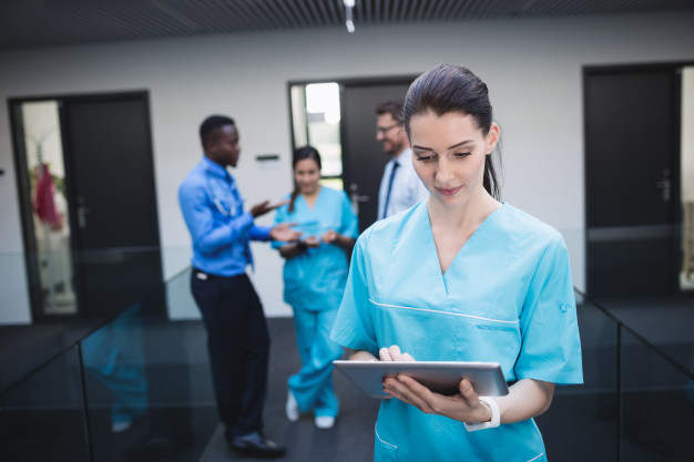 nurse-using-digital-tablet-hospital-corridor_107420-84829