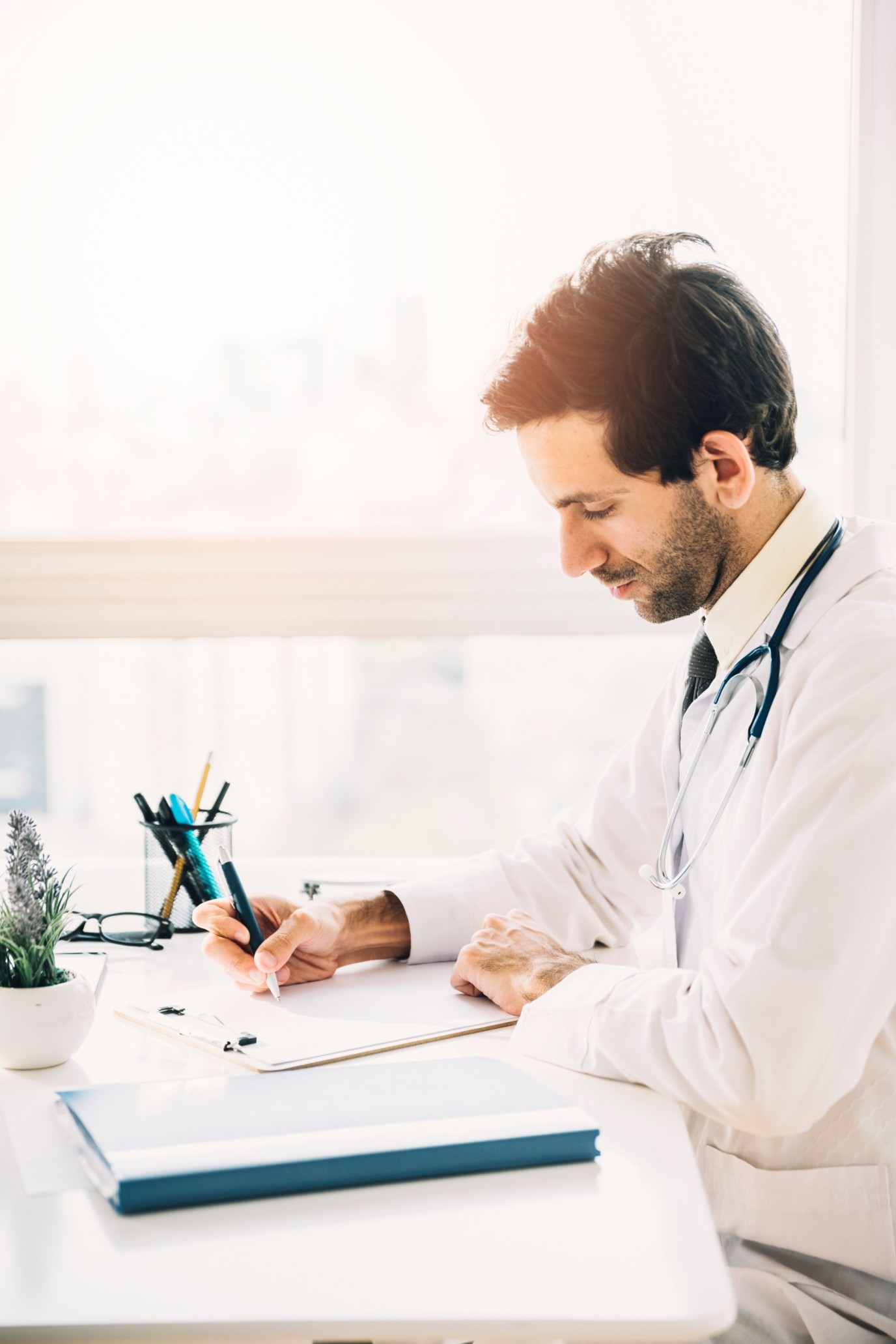 side-view-young-male-doctor-writing-clipboard-clinic (1) (1) (1)