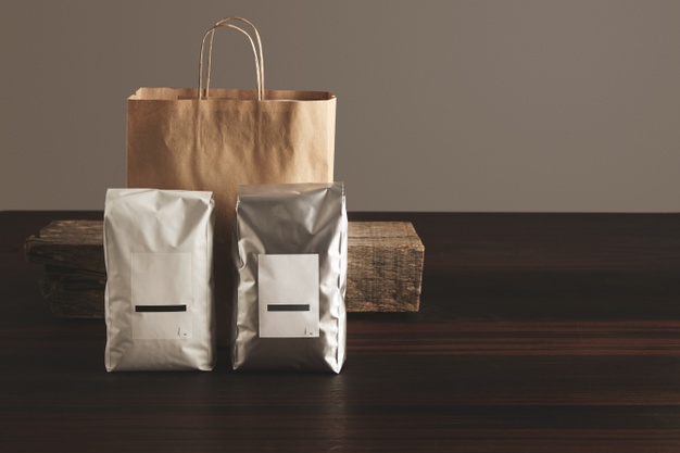 two-big-hermetic-packages-with-blank-labels-presented-front-craft-paper-bag-rustic-wooden-brick-red-table_346278-406