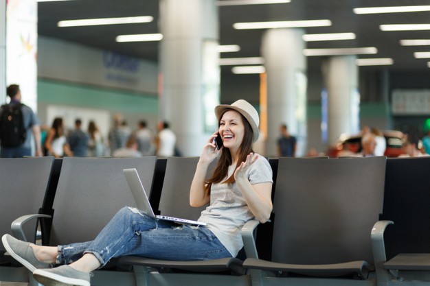 young-laughing-traveler-tourist-woman-working-laptop-talk-mobile-phone-calls-friend-booking-taxi-hotel-wait-lobby-hall-airport_365776-4651