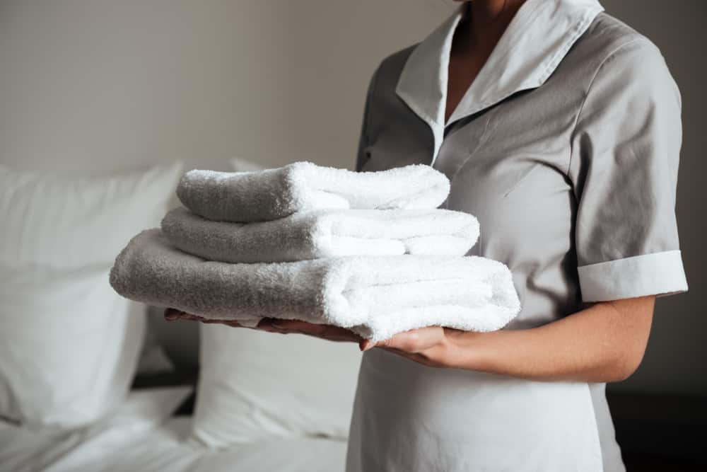 young-hotel-maid-standing-holding-fresh-clean-towels